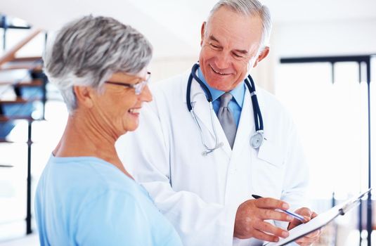 Doctor discussing medical report. Smiling mature doctor discussing medical report with happy patient.