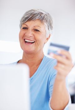 Smiling mature woman shopping online. Smiling mature woman shopping online using credit card and laptop.