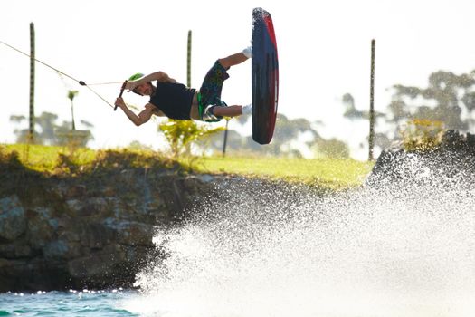 Hang loose. Young man kicks up waterspray on his wakeboard while doing a jump - copyspace.