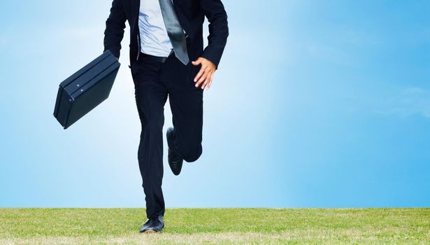 Male business executive running with a briefcase on a field. Cropped image of a male business executive running with a briefcase on a field - Copyspace.