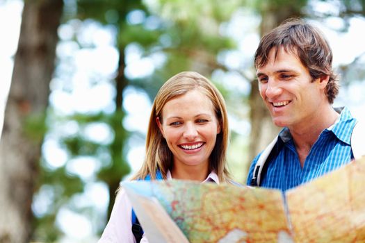 Couple taking a look at map. Couple with backpack taking a look at map and smiling.