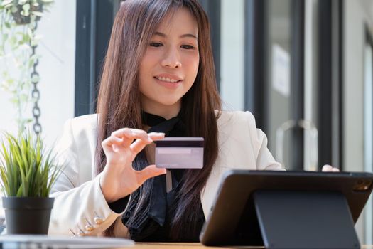 Portrait of Asian young woman using a mobile phone and credit card for online shopping