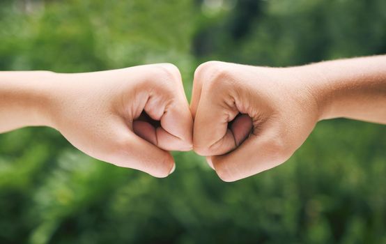 Closeup of a fist bump outside in nature. Two diverse peoples hands greeting. Fist bump in nature. Closeup of a fist bump outside in nature. Two diverse peoples hands greeting. Fist bump in nature.