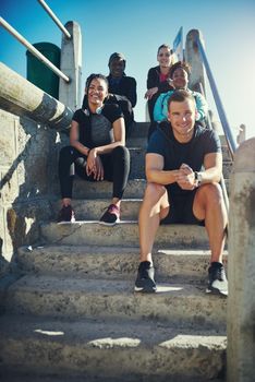We find it better to workout with buddies. Portrait of a group of sporty young people taking a break while exercising outdoors.