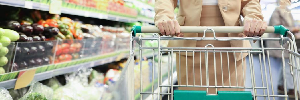 Smiling woman with shopping cart in supermarket buying groceries food