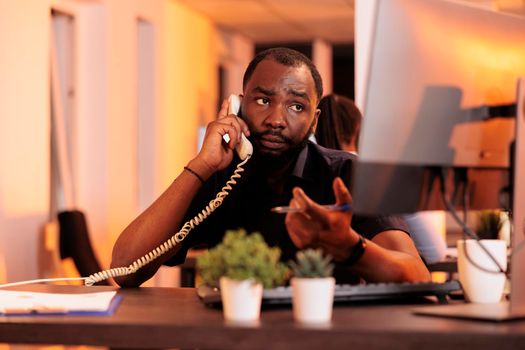 Young businessman talking to people on landline phone