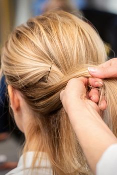 Hairdresser's hands braiding client's hair