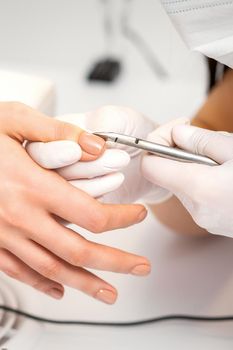 Manicure master is removing cuticles