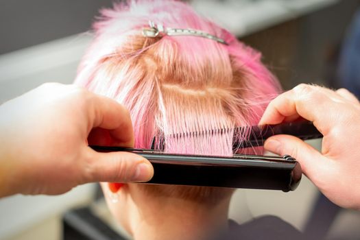 Hairdresser straightening short pink hair