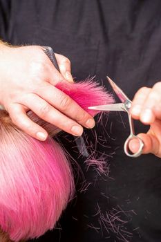 Hairdresser cutting short pink hair