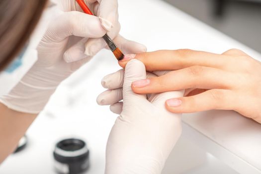 Manicurist covering nails with transparent polish