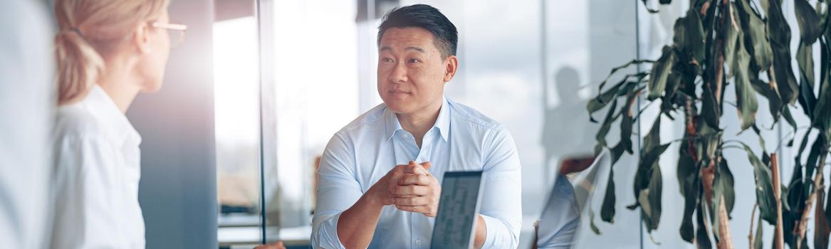 Young Asian businessman listening his colleagues on meeting in modern office
