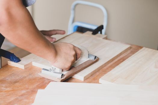 Woodworking entrepreneurs are using sandpaper to decorate wooden pieces to assemble and build wooden tables for their clients.