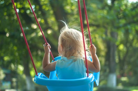toddler girl on a swing in the park