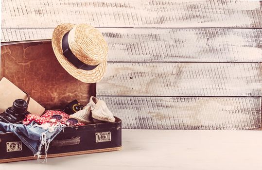 retro bag for summer vocation with photo camera, book and wicker hat