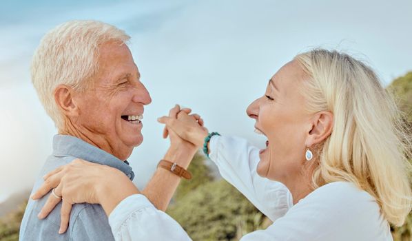 A happy mature caucasian couple enjoying fresh air on vacation at the beach. Smiling retired couple dancing outside