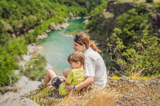 Mother and son tourists on background of purest waters of the turquoise color of the river Moraca flowing among the canyons. Travel around Montenegro concept