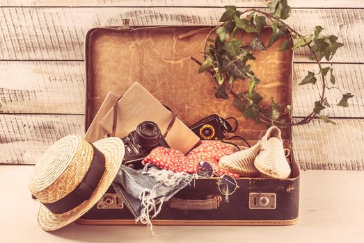 retro bag for summer vocation with photo camera, book and wicker hat