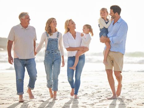 Multi generation family holding hands and walking along the beach together. Caucasian family with two children, two parents and grandparents enjoying summer vacation