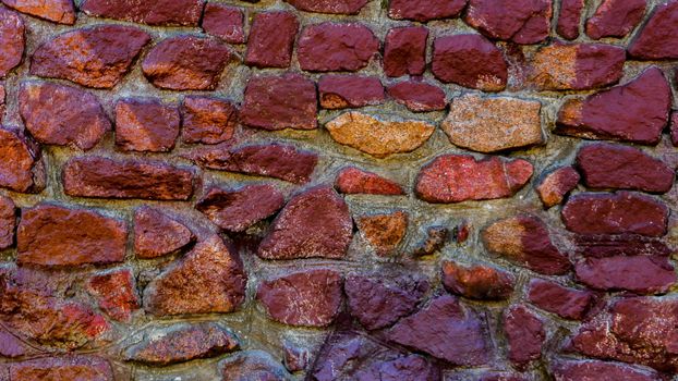 A fragment of a wall made of stones of different colors.