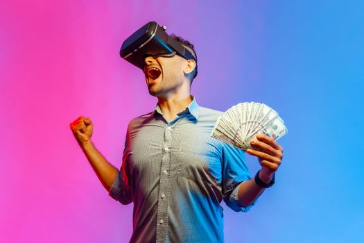 Man holds dollars illusion of rich millionaire yelling with excitement, playing virtual reality game