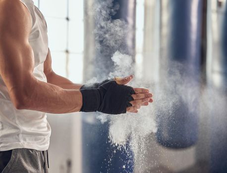 Mma fighter prepare for boxing routine. Combat using chalk to prepare for training workout. Boxer getting ready with dust for combat workout. Athlete using dust on their hands cropped in the gym