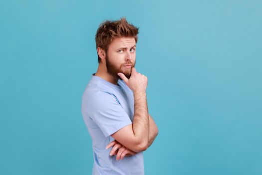 Man in T-shirt touching chin while pondering plan, having doubts about difficult choice, not sure.