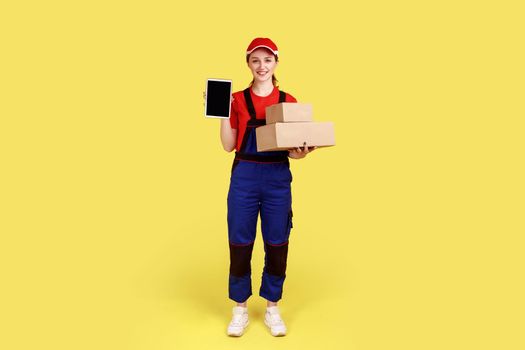 Courier woman holding parcels for delivery and showing tablet with blank screen for advertisement.