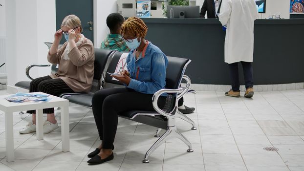 Diverse group of patients with face masks sitting in waiting area