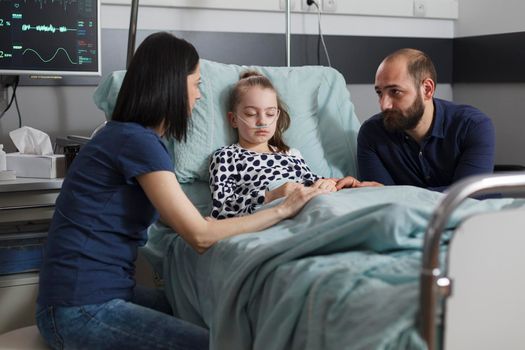 Worried parents sitting beside sick daughter hospitalized