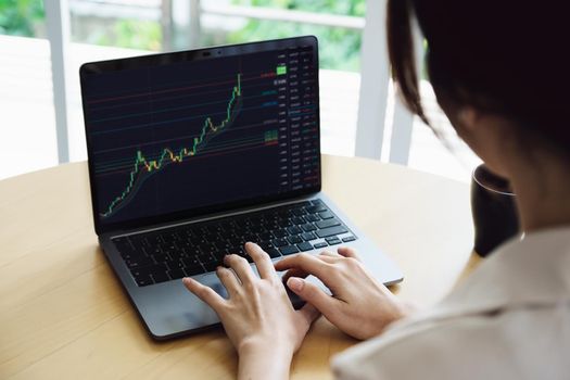 New normal, self-employed women are using a computer laptop to trade stocks for profit, buying and selling