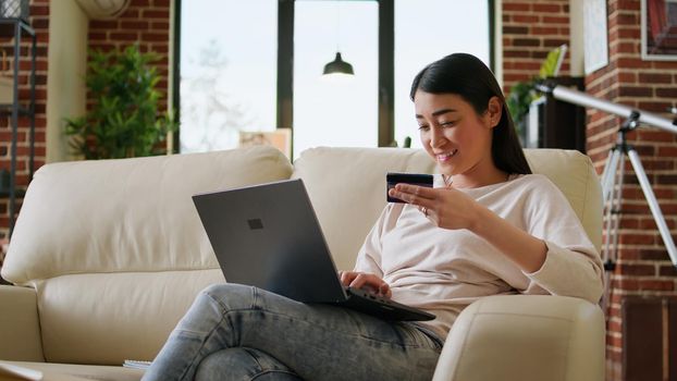 Happy young adult woman inserting credit card credentials on on shopping site for online payment