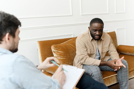 An African-American man talks to a psychologist about his problems. Psychological help service.