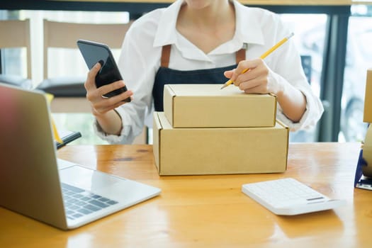 Start up small business owner writing address on cardboard box a.
