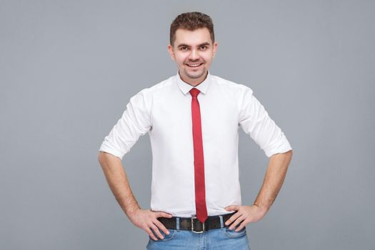 man standing with hands on hips and looking at camera with toothy smile