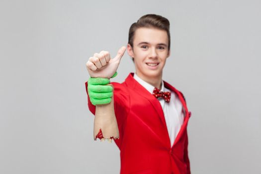 Portrait of cheerful gentleman smiling at camera and holding zombie hand showing thumbs up, like gesture. white background