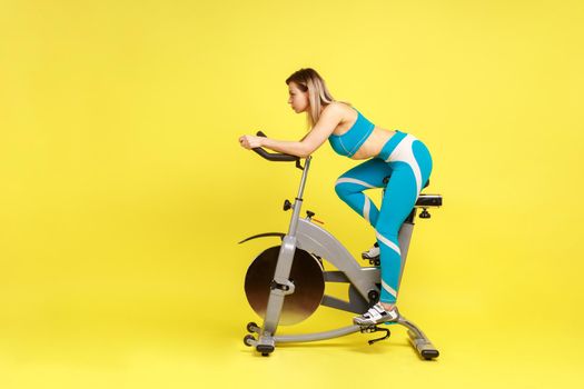 Woman with perfect body riding exercise bike at home, making an effort to lose a few extra pounds.