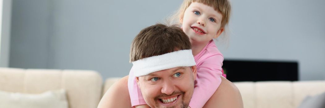 Father and daughter spend time at home, sport activity with child on back