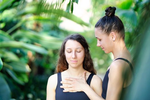 Yoga concept, meditation and sound therapy. Beautiful young girl at yoga session with her yoga and meditation teacher at tropical yoga retrear