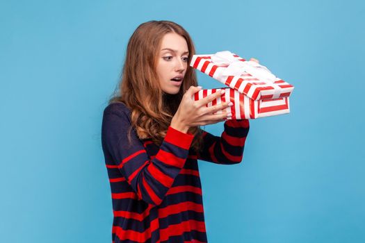 Woman looking inside present box with scared expression, getting bad gift, being disappointed.