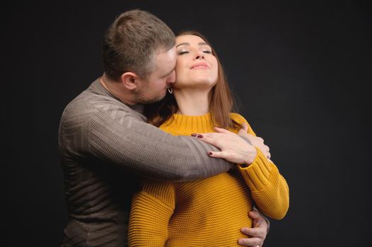 Cute couple in love kissing and hugging in the studio on a black background
