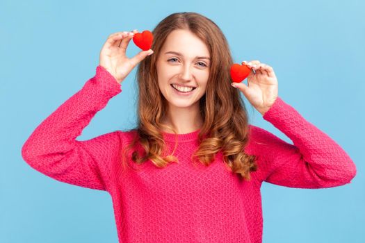 Woman having fun with red toy hearts, showing his fondness and devotion, romance.
