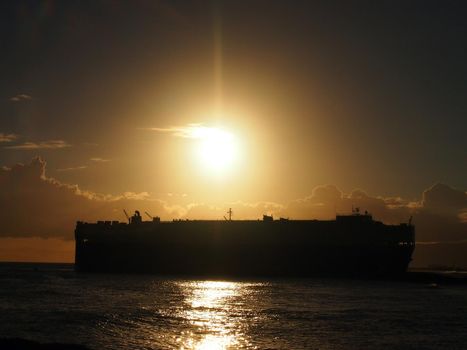 Dramatic Sunset over Pacific Ocean with Cargo Ship passing through