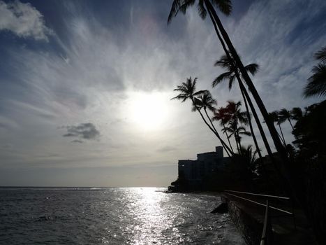 Sunsets over Waikiki waters as waves crash on sea wall at Makalei Beach Park