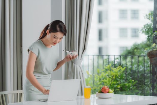 woman eating breakfast and busy working at home
