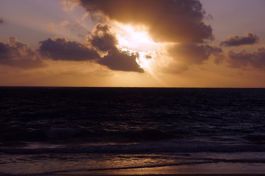 Early Morning Sunrise on Waimanalo Beach over ocean bursting through the clouds