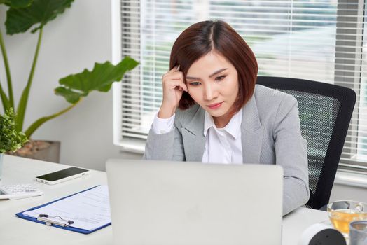  Depressed stressed young Asian business woman with laptop suffering from trouble