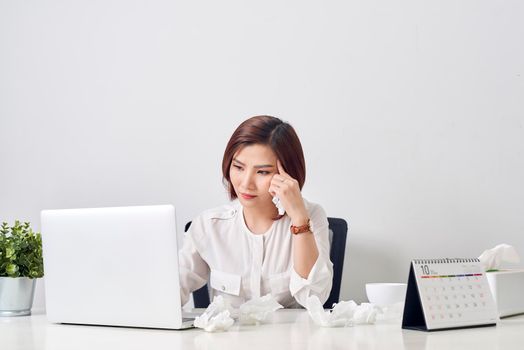Sad exhausted woman with tissue suffering from cold while working with laptop at table