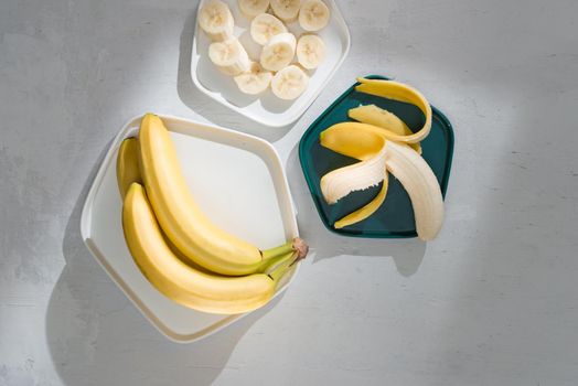 Yummy bananas and bowl with slices on wooden background