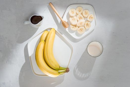 Yummy bananas and bowl with slices on wooden background